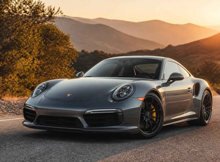 Srebrne Porsche 911 zaparkowane na górskiej drodze o zachodzie słońca